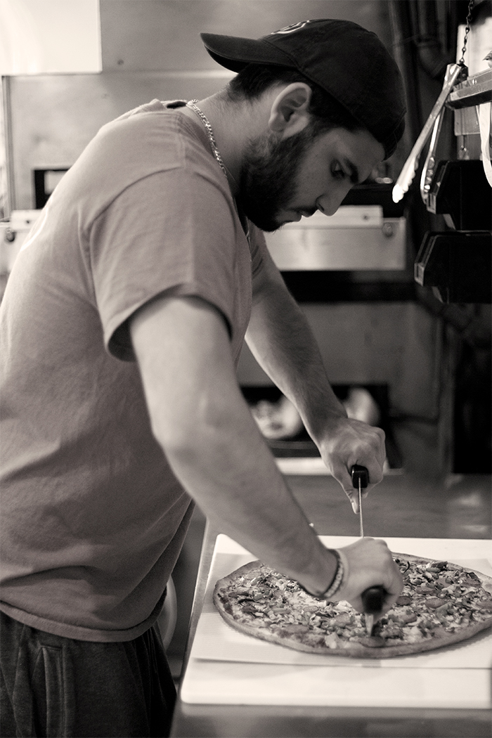A man making a pizza in a restaurant kitchen